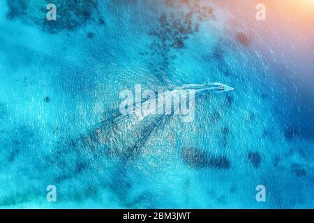 Vue aérienne du bateau flottant dans l'eau transparente au coucher du soleil Banque D'Images