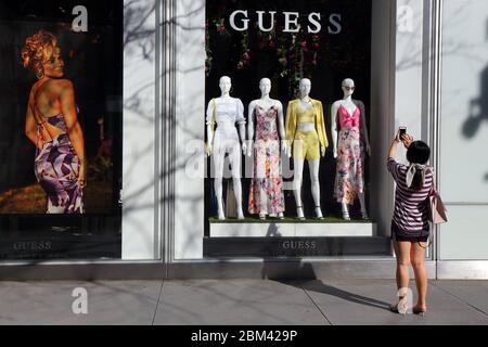 Une personne prend une photo de la mode printanière pendant que la fenêtre de shopping à GUESS, 575 Fifth Ave, New York Banque D'Images