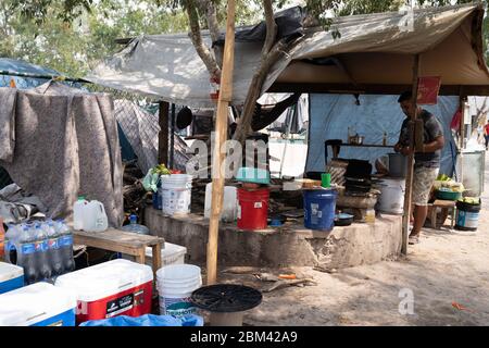 Matamoros, Mexique. 06e mai 2020. Un homme prépare de la nourriture dans une cuisine sophistiquée composée d'un tambour de lave-linge au milieu du camp de réfugiés. Credit: Lexie Harrison-Cripps/Alay Live News Banque D'Images