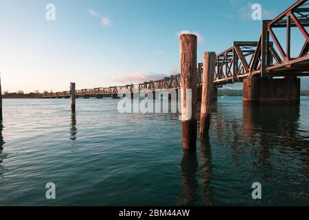 Pont ferroviaire historique à structure de treillis traversant le port de Tauranga, au petit matin. Banque D'Images