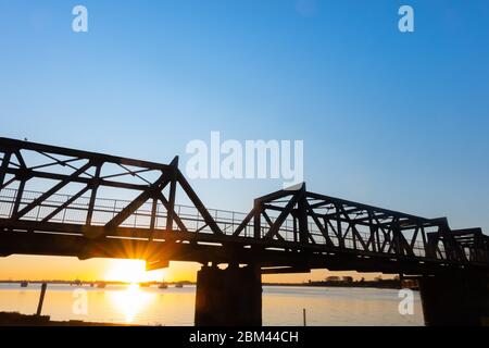 Pont ferroviaire silhoueté par le lever du soleil à travers le port de Tauranga en Nouvelle-Zélande. Banque D'Images