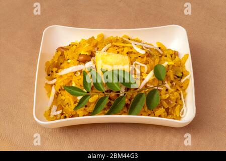 Poha plat de petit déjeuner indien sain et populaire fait avec du riz aplati servi dans l'assiette. Banque D'Images