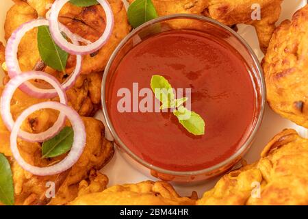 Pakora à l'oignon et chutney délicieux en-cas indien servi dans un bol à plat. Banque D'Images