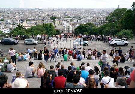 La vue de la ville de Paris avec des foules se reposant sur les escaliers de la Basilique du Sacré-Cœur de Montmartre et de la rue du Cardinal Dubois en premier plan.Paris.France Banque D'Images