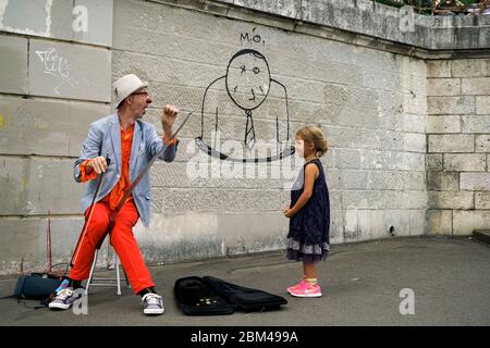 Un clown interprète de rue jouant de la musique pour une jeune fille à Montmartre.Paris.France Banque D'Images