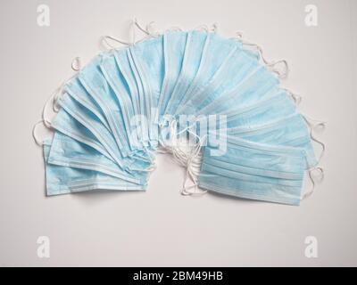 Plusieurs masques jetables bleu clair sur fond blanc. Banque D'Images