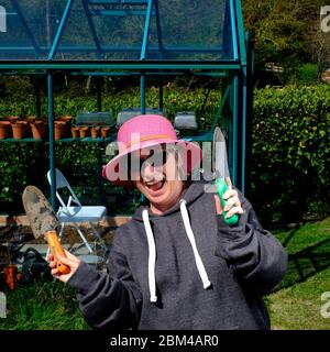 Femme appréciant le jardinage pendant la quarantaine verrouillage pandémie globale Covid-19 dans son propre jardin de chalet Banque D'Images