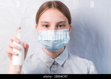 adolescente de 12-15 ans, dans un masque médical protecteur tient un antiseptique dans sa main, la désinfection de lavage des mains, hôpital de quarantaine et soi-même Banque D'Images