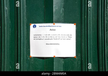 Faro, Portugal - 16 mars 2020 : message imprimé sur l'église en langue portugaise informant les gens de la fermeture en raison du coronavirus, l'épidémie de COVID-19. Pandémie de COV-SRAS-2. Culte annulé. Banque D'Images
