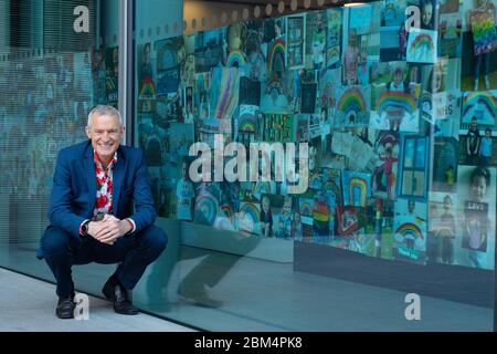 Jeremy Vine avec des photos de l'arc-en-ciel envoyées par les spectateurs de son émission Channel 5, exposées dans les fenêtres du bâtiment ITN, dans le centre de Londres, en hommage aux principaux travailleurs qui luttent contre l'épidémie de coronavirus. Banque D'Images