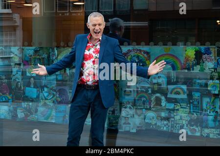 Jeremy Vine avec des photos de l'arc-en-ciel envoyées par les spectateurs de son émission Channel 5, exposées dans les fenêtres du bâtiment ITN, dans le centre de Londres, en hommage aux principaux travailleurs qui luttent contre l'épidémie de coronavirus. Banque D'Images