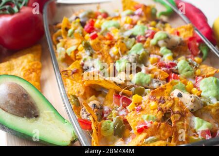 Plat de nacho cuit dans un moule en verre avec une puce de tortilla de maïs, une salsa pico de gallo, un chipotle de guacamole d'avocat, des haricots, des jalapenos et un jack de Monterrey c Banque D'Images
