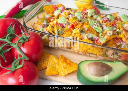 Plat de nacho cuit dans un moule en verre avec une puce de tortilla de maïs, une salsa pico de gallo, un chipotle de guacamole d'avocat, des haricots, des jalapenos et un jack de Monterrey c Banque D'Images