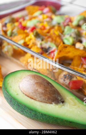 Plat de nacho cuit dans un moule en verre avec une puce de tortilla de maïs, une salsa pico de gallo, un chipotle de guacamole d'avocat, des haricots, des jalapenos et un jack de Monterrey c Banque D'Images