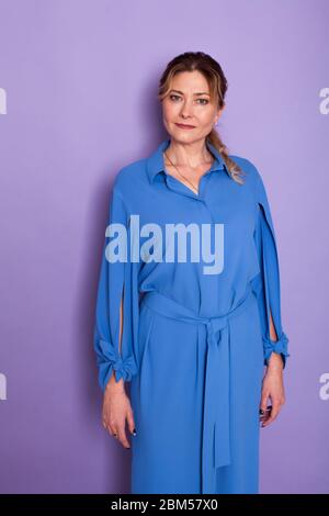 belle femme de 40 ans dans une robe bleue sur fond violet Banque D'Images