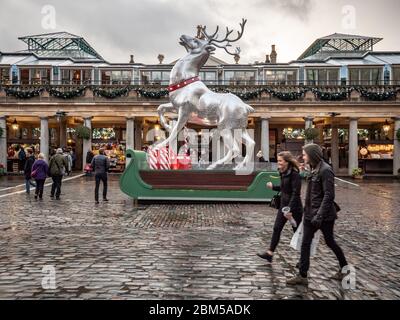 Noël au Covent Garden. Les clients qui se prominent à côté d'un étalage de Noël élaboré à l'extérieur du quartier populaire des marchés de Londres. Banque D'Images