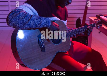 Créer de la musique et un studio d'enregistrement concept - African american man guitariste enregistrement de piste de guitare électrique dans le studio à domicile, gros plan. Banque D'Images