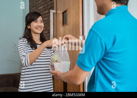 Liveur de nourriture à une femme à la maison. Concept de service de vente de nourriture en ligne Banque D'Images