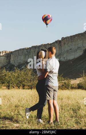 Un jeune couple se dresse face à face et se cache la tête derrière un ladies hat. Peut-être qu'ils rêvent de quelque chose et leur rêve est comme un ballon s Banque D'Images