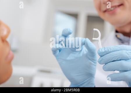 vue rognée du dentiste dans des gants en latex tenant le bâton de soie près d'une femme afro-américaine Banque D'Images