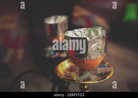 Narguilé avec du tabac aromatisé sur un bol de fruits orange recouvert d'un papier d'aluminium pour économiser la chaleur de la bobine.Traditioanl est pipe de shisha dans le salon café.détendez-vous et fumée s Banque D'Images