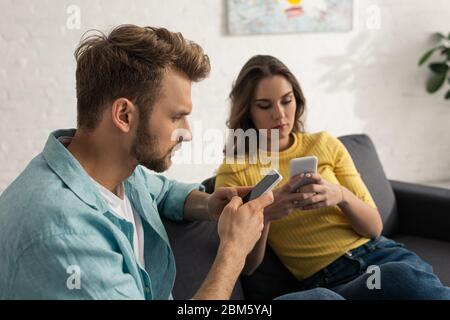 Attention sélective de couple addicted en utilisant des smartphones sur le canapé Banque D'Images