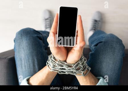 Vue de dessus d'un homme avec des mains liées et un smartphone à chaîne Banque D'Images