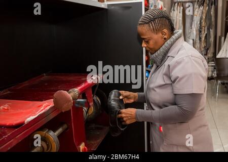 Johannesburg, Afrique du Sud - 25 mai 2015 : femme africaine travaillant dans une franchise de réparation de chaussures et de nettoyage à sec Banque D'Images
