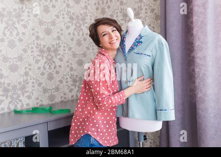 Femme mode designer robe sur mannequin. Couturière ou chemise de maintien sur mesure sur maquette dans le studio de design créatif à la maison. La confection de vêtements crée ou Banque D'Images