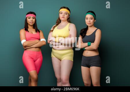 Sportswomen avec bras croisés regardant la caméra sur fond vert Banque D'Images
