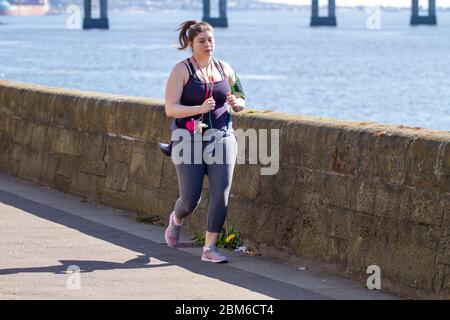 Dundee, Tayside, Écosse, Royaume-Uni. 7 mai 2020. Météo au Royaume-Uni : une matinée chaude et ensoleillée à Dundee avec des températures atteignant 19°C. Une jeune fille aux courbes qui profite du temps glorieux tout en faisant des exercices en plein air, qui fait du jogging le long de la promenade du bord de mer pendant les restrictions de maintien de Covid-19. Crédit : Dundee Photographics/Alamy Live News Banque D'Images