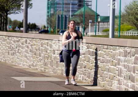 Dundee, Tayside, Écosse, Royaume-Uni. 7 mai 2020. Météo au Royaume-Uni : une matinée chaude et ensoleillée à Dundee avec des températures atteignant 19°C. Une jeune fille aux courbes qui profite du temps glorieux tout en faisant des exercices en plein air, qui fait du jogging le long de la promenade du bord de mer pendant les restrictions de maintien de Covid-19. Crédit : Dundee Photographics/Alamy Live News Banque D'Images