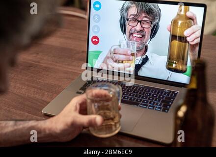 Des amis de longue date bavardant et buvant de la bière lors d'un appel vidéo, des collègues de travail célèbrent un succès à long terme en dégustant de la bière, en s'ivrant pendant un appel Banque D'Images
