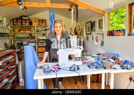 L'artiste Shelley Dyer Gibbins, 47 ans, du village de Croscombe, près de Wells, dans son studio, où elle a fait des masques faciaux de designer pour les 600 résidents du village de Somerset, à partir de matériaux de masques de qualité médicale et de certains de ses documents imprimés d'art qu'elle avait laissés. Banque D'Images