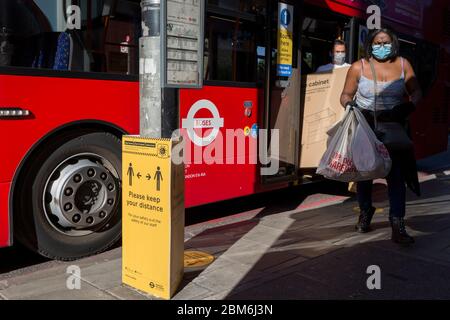 Le nombre de nouveaux cas de coronavirus au Royaume-Uni s'élève à 201,101, avec un nombre de décès au Royaume-Uni de 30,076, le plus élevé enregistré en Europe, Les passagers quittent un bus à côté d'un panneau transport pour Londres (TFL) demandant au public de maintenir des distances sociales sûres lorsqu'ils voyagent dans les transports en commun de la capitale pendant le confinement continu de Covid, le 6 mai 2020, dans le sud de Londres, en Angleterre. Les portes d'entrée des bus londoniens sont maintenant désactivées pour éviter l'exposition des conducteurs au virus, et aucun tarif n'est pris sur les voyages pour éviter davantage le contact avec le lecteur de carte. Banque D'Images