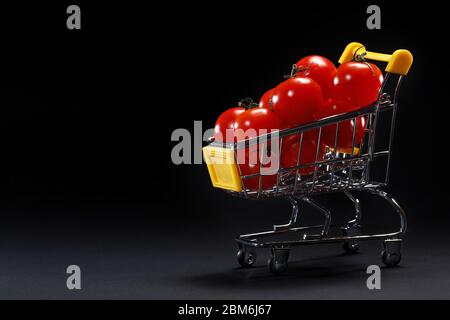 Mini panier avec tomates cerises fraîches sur fond noir. Espace de copie de publicité de supermarché. Épicerie. Livraison de tomates. Transport Banque D'Images