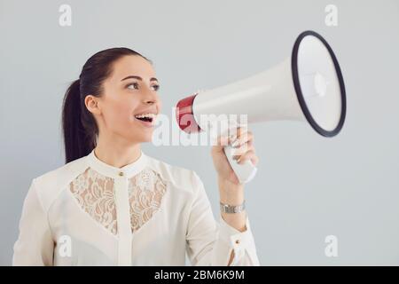 Une femme dans une chemise blanche dans une corne de taureau sur fond gris. Banque D'Images