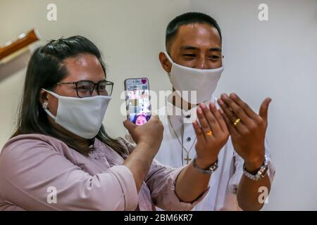 Quezon City, Philippines. 7 mai 2020. Un couple nouvellement-mer montre leurs anneaux de mariage à des amis par un appel vidéo lors d'une cérémonie de mariage à Quezon City, aux Philippines, le 7 mai 2020. Les Philippines ont signalé jeudi 339 nouveaux cas de COVID-19, portant le nombre total des cas de COVID-19 dans le pays à 10,343. Crédit: Rouelle Umali/Xinhua/Alay Live News Banque D'Images