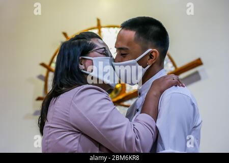 Quezon City, Philippines. 7 mai 2020. Un couple nouvellement-mer portant des masques de visage s'embrasse lors d'une cérémonie de mariage à Quezon City, aux Philippines, le 7 mai 2020. Les Philippines ont signalé jeudi 339 nouveaux cas de COVID-19, portant le nombre total des cas de COVID-19 dans le pays à 10,343. Crédit: Rouelle Umali/Xinhua/Alay Live News Banque D'Images