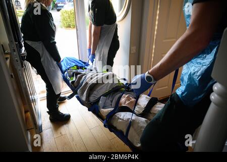 NOTE DE LA RÉDACTION : le patient a donné son consentement pour être photographié. Une équipe d'ambulance portant des vêtements de protection transporte une patiente de son domicile dans une Sling de Southampton après avoir répondu à un appel de 999 près de Portsmouth, Hampshire. Banque D'Images