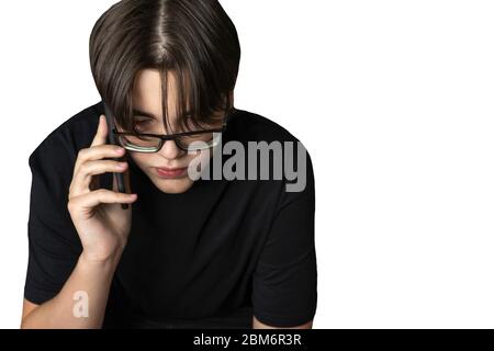 un adolescent dans une chemise noire et des lunettes qui parle au téléphone. isoler sur fond blanc Banque D'Images