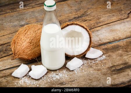 Image concept de noix de coco avec bouteille de lait sur fond de bois Banque D'Images