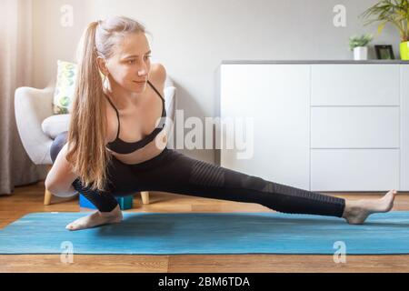 Jeune femme souriante faisant Marichyasana pose de yoga à la maison Banque D'Images