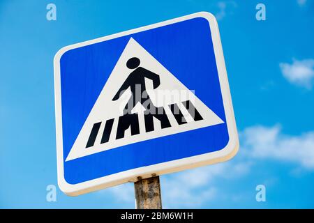 Vue à angle bas du panneau de signalisation de passage piéton espagnol, sur fond de ciel bleu avec de petits nuages. Banque D'Images