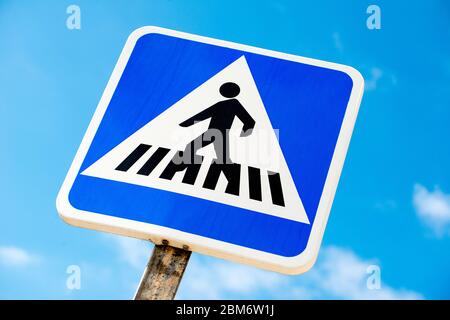 Vue à angle bas du panneau de signalisation de passage piéton espagnol, sur fond de ciel bleu avec de petits nuages. Banque D'Images