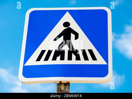 Vue à angle bas du panneau de signalisation de passage piéton espagnol, sur fond de ciel bleu avec de petits nuages. Banque D'Images