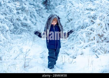 Des enfants heureux sur les promenades dans la nature en hiver. Bien habillé en profitant de l'hiver. Portrait d'hiver d'un enfant mignon heureux Banque D'Images