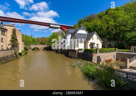 Rivière Alzette à Pfaffenthal, Luxembourg, avec maisons sur les rives de la rivière. En arrière-plan la Tour Vauban et le pont rouge de la Grande Duchesse Charlotte. Banque D'Images