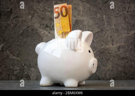 Cinquante Euro billet dans une fente de piggy Bank. Concept d'épargne financière. Banque D'Images
