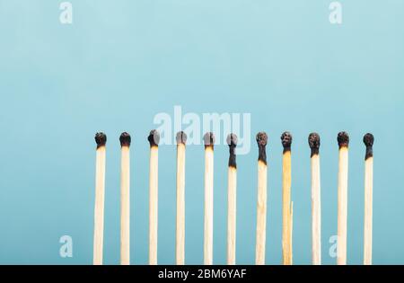 Une rangée de onze allumettes brûlées sur fond bleu. Banque D'Images